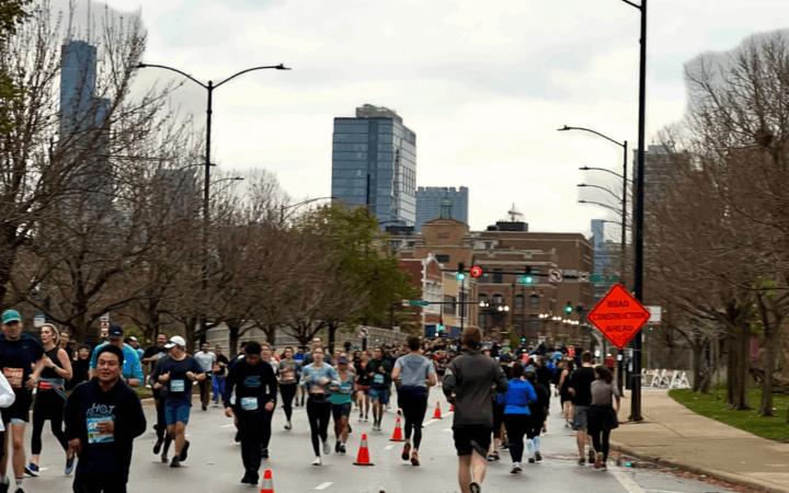 Runners crossing downtown Chicago streets during the 2025 Chicago Marathon with cheering crowds.