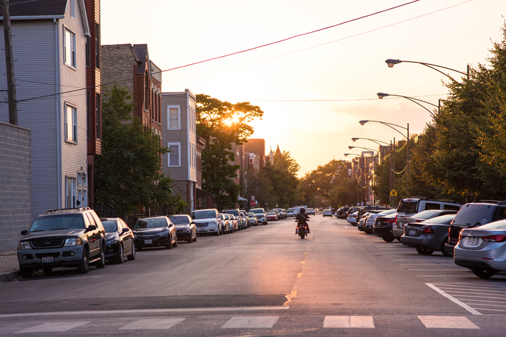 A person rides a motorcycle into the sunset on a neighborhood street in Chicago. Chicago has many popular neighborhoods close enough to downtown for a quick commute.